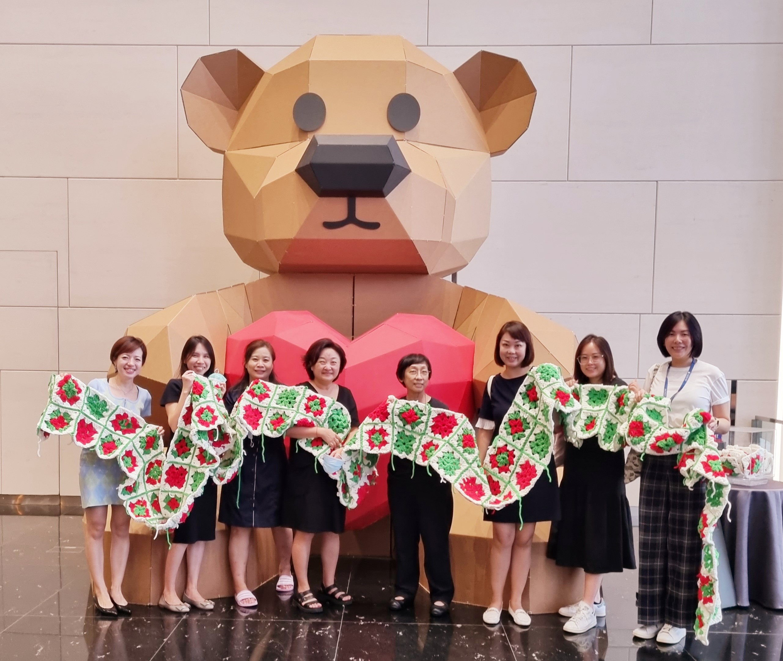 Roxanne Lee (first from left), Head of Community Management, Commercial, Frasers Property Singapore with tenants from Frasers Tower and their completed 13-metre long scarf for our adopted bear.