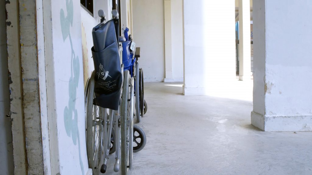 A line-up of wheelchairs outside MASTC belonging to clients, waiting to be fixed, with more around the void deck.
