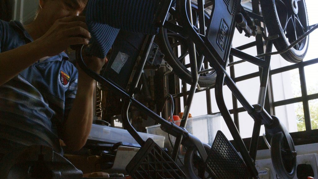 A volunteer in the MASTC workshop fixing a wheelchair.