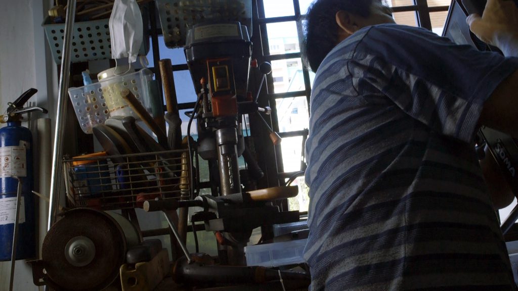 Volunteer working on a wheelchair in the workshop, surrounded by tools and spare-parts.